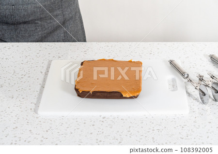 Scoring caramel fudge using a wheel dough cutter for cutting into small square pieces. 108392005