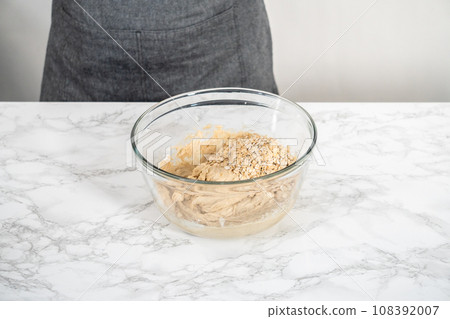 Mixing ingredients in a large glass mixing bowl to bake banana oatmeal muffins. 108392007