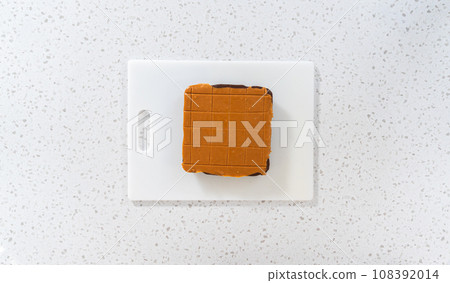 Flat lay. Scoring caramel fudge using a wheel dough cutter for cutting into small square pieces. Flat lay. Scoring caramel fudge using a wheel dough cutter for cutting into small square pieces. 108392014