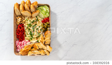 Flat lay. A large vegetarian party butter board with fresh and pickled vegetables and sliced french baguette for a party. 108392016