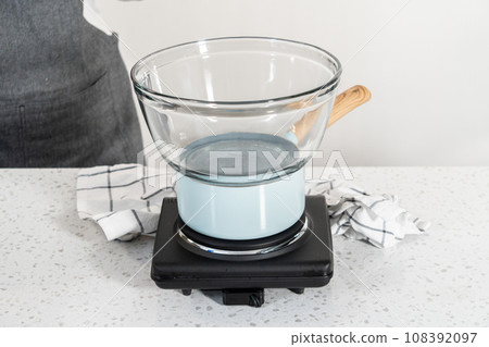 Melting white chocolate chips and other ingredients in the double boiler to prepare chocolate pistachio fudge. Melting white chocolate chips and other ingredients in the double boiler to prepare chocolate pistachio fudge. 108392097