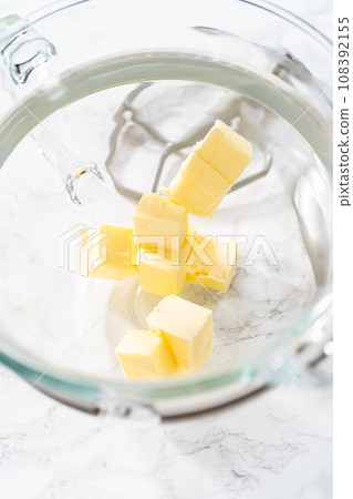 Mixing ingredients in kitchen electric mixer to make lemon buttercream frosting. 108392155