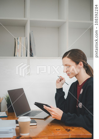 Female business woman using tablet and laptop for analyzing the business report in the office Female business woman using tablet and laptop for analyzing the business report in the office 108392284