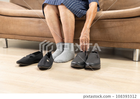 Elderly woman put on and take off shoes at home 108393312