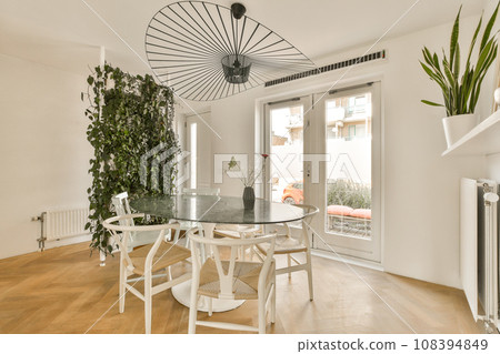 a dining table and chairs in a living room with an air plant on the wall next to the glass door 108394849
