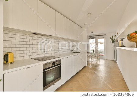 a modern kitchen with white cabinets and wood flooring in the middle of the room, there is an oven on the wall a modern kitchen with white cabinets and wood flooring in the middle of the room, there is an oven on the wall 108394869