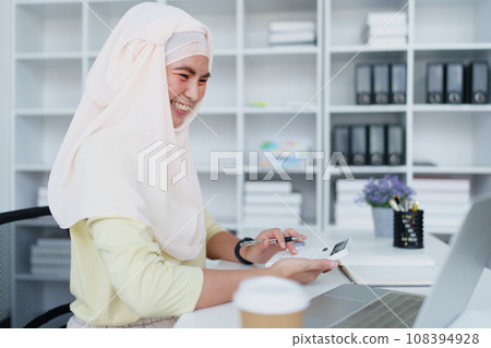 Muslim women use calculators, computers, and laptops to check their accounts at work Muslim women use calculators, computers, and laptops to check their accounts at work 108394928