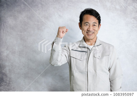 Smiling man in work clothes doing a fist pump 108395097