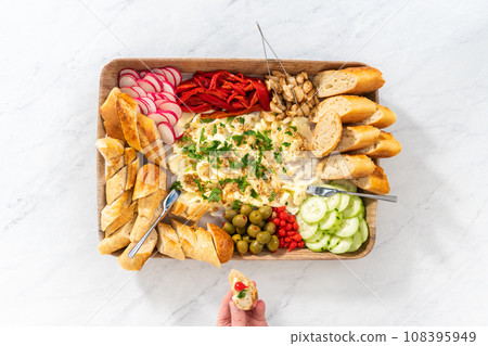 Flat lay. A large vegetarian party butter board with fresh and pickled vegetables and sliced french baguette for a party. Flat lay. A large vegetarian party butter board with fresh and pickled vegetables and sliced french baguette for a party. 108395949