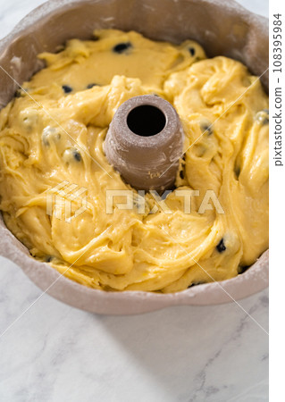 Filling metal bundt cake pan with cake butter to bake lemon blueberry bundt cake. Filling metal bundt cake pan with cake butter to bake lemon blueberry bundt cake. 108395984