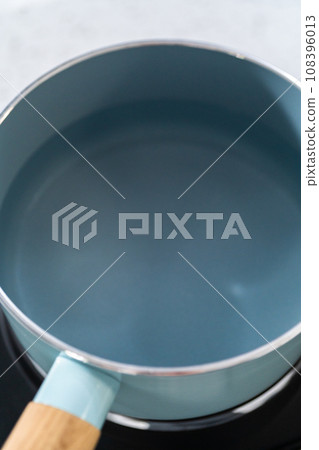 Melting chocolate chips and other ingredients in a glass mixing bowl over boiling water to prepare chocolate fudge with peanut butter swirl. 108396013