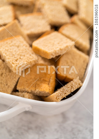 Baking bread pudding with raising and almond slivers in a white casserole dish. Baking bread pudding with raising and almond slivers in a white casserole dish. 108396018