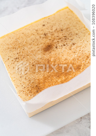 Removing eggnog fudge from a square cheesecake pan lined with parchment. Removing eggnog fudge from a square cheesecake pan lined with parchment. 108396020