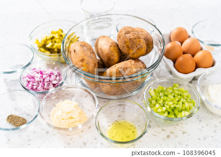 Measured ingredients in glass mixing bowls to make potato salad. 108396045