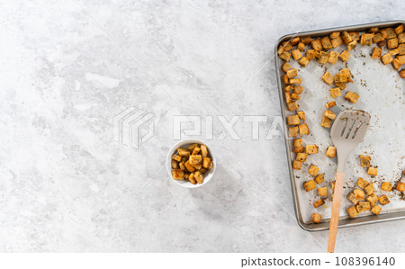 Flat lay. Cooling freshly dried croutons on a baking sheet lined with parchment paper. Flat lay. Cooling freshly dried croutons on a baking sheet lined with parchment paper. 108396140