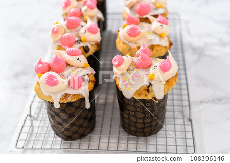Decorating mini Easter bread kulich with sprinkles and meringue bird-shaped cookies. Decorating mini Easter bread kulich with sprinkles and meringue bird-shaped cookies. 108396146