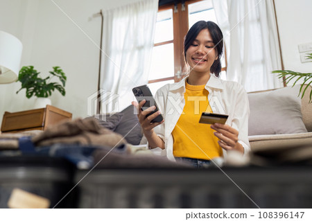 Happy young woman with credit card booking vacation at travel agency or making hotel reservation online Happy young woman with credit card booking vacation at travel agency or making hotel reservation online 108396147