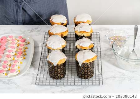 Glazing mini Easter bread kulich with a white lemon glaze. Glazing mini Easter bread kulich with a white lemon glaze. 108396148