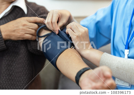 Nurses or caregivers take care of elderly by helping to check their blood pressure Nurses or caregivers take care of elderly by helping to check their blood pressure 108396173