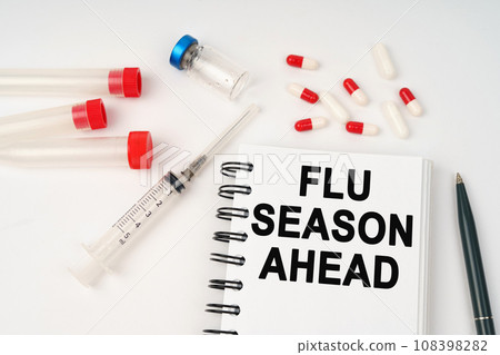 On the table are pills, injections, a syringe and a notepad with the inscription - flu season ahead On the table are pills, injections, a syringe and a notepad with the inscription - flu season ahead 108398282