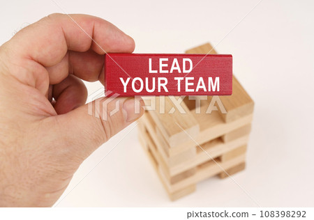 In the hands of a man there is a red wooden plate with the inscription - Lead Your Team In the hands of a man there is a red wooden plate with the inscription - Lead Your Team 108398292
