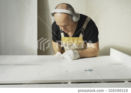 A worker fastens the parts of a bed using a confirmat. 108398328