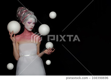 Gorgeous woman witch fairy with pink and white skin holding white planet spheres on black background 108398696
