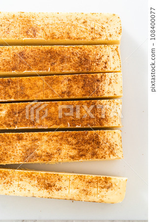 Cutting eggnog fudge into small pieces on a white cutting board. Cutting eggnog fudge into small pieces on a white cutting board. 108400077