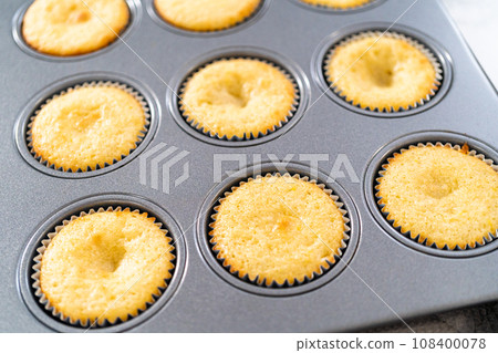 Cooling freshly baked lemon cupcakes on a kitchen counter. 108400078