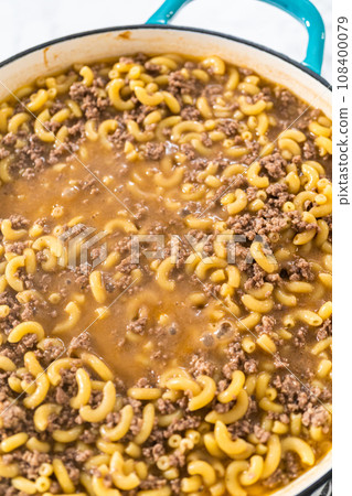 Cooking homemade hamburger helper in enameled cast iron skillet. 108400079
