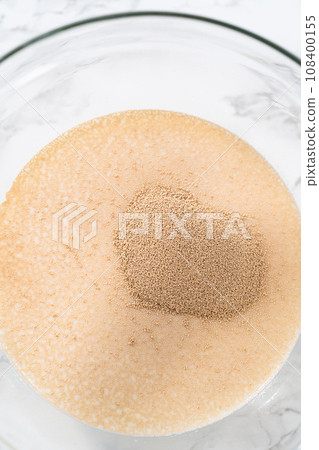 Activating dry yeast in a glass mixing bowl to bake mini Easter bread kulich. 108400155