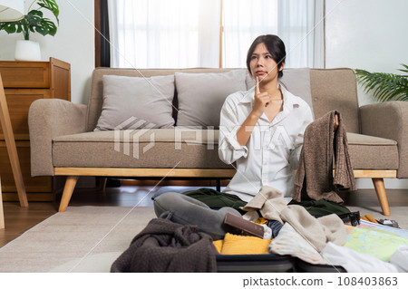 Young woman sit in floor and preparation suitcase for travelling at weekend trip Young woman sit in floor and preparation suitcase for travelling at weekend trip 108403863