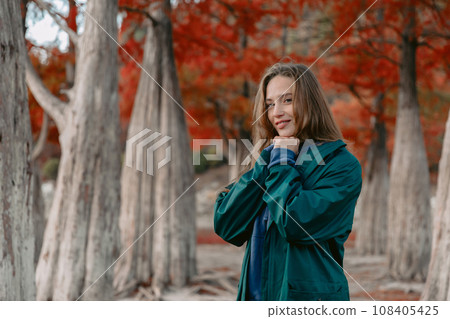 Attractive woman in the park and looking at the camera. People in autumnal forest. Attractive woman in the park and looking at the camera. People in autumnal forest. 108405425