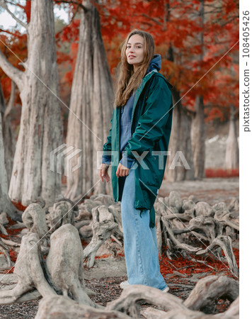 Young woman walking down the park and looking at the camera. People in autumnal forest. Young woman walking down the park and looking at the camera. People in autumnal forest. 108405426