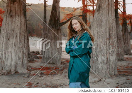 Portrait of attractive woman walking down the park and looking at the camera. People in autumnal forest. Portrait of attractive woman walking down the park and looking at the camera. People in autumnal forest. 108405430