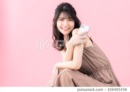 Middle-aged woman looking at smartphone with pink background 108405436