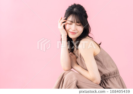 A middle-aged woman doing skin care with a pink background A middle-aged woman doing skin care with a pink background 108405439