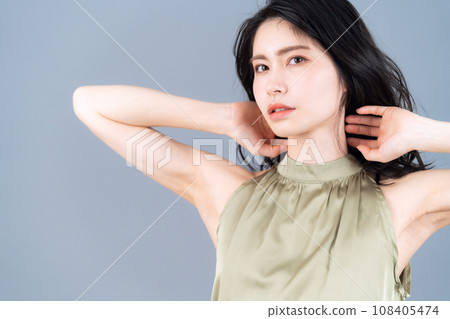 A middle-aged woman doing skin care against a gray background 108405474