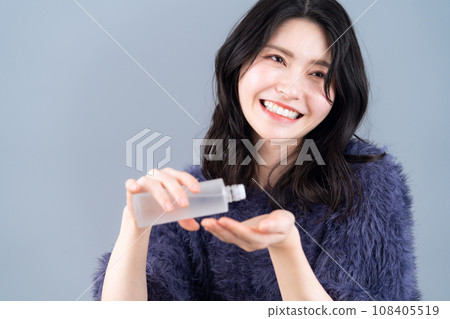 A middle-aged woman doing skin care against a gray background A middle-aged woman doing skin care against a gray background 108405519