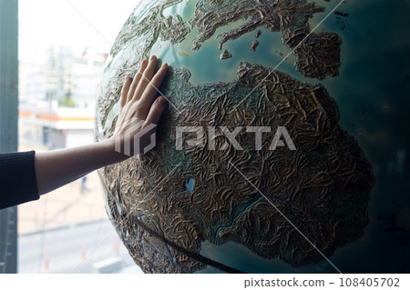 Child holding hand on globe. A child hand on a large model of the planet earth. The concept of protecting the environment, caring for nature and believing in a bright future. Globe and children 108405702