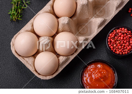 Raw chicken eggs in a box, cherry tomatoes, chickpeas, spices, salt and herbs Raw chicken eggs in a box, cherry tomatoes, chickpeas, spices, salt and herbs 108407011