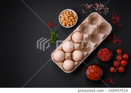 Raw chicken eggs in a box, cherry tomatoes, chickpeas, spices, salt and herbs 108407014