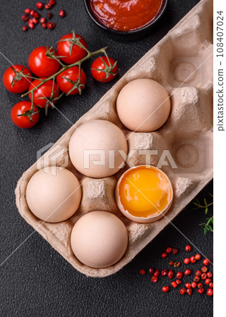 Raw chicken eggs in a box, cherry tomatoes, chickpeas, spices, salt and herbs Raw chicken eggs in a box, cherry tomatoes, chickpeas, spices, salt and herbs 108407024