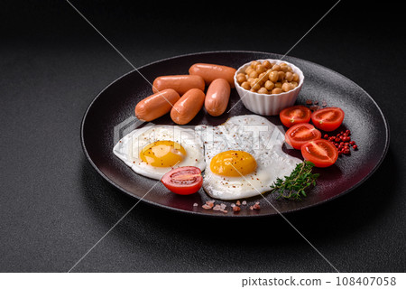 Fried chicken eggs, sausages, cherry tomatoes, chickpeas, spices, salt and herbs 108407058