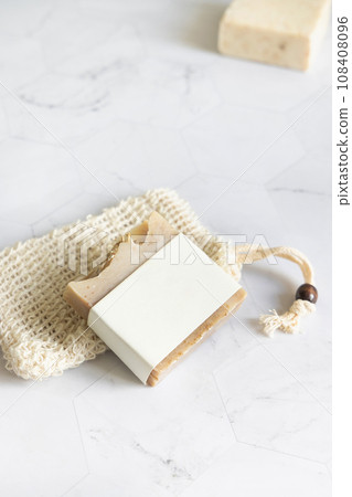 Beige handmade soap bar with blank label on soap saver bag close up, mockup 108408096