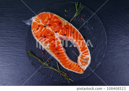 Raw salmon steak with spices on black slate. Top view Raw salmon steak with spices on black slate. Top view 108408521
