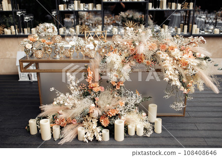 Front view of glamour table against mirrored wall with floating candles. Modern luxury wedding decor in expensive tones. Front view of glamour table against mirrored wall with floating candles. Modern luxury wedding decor in expensive tones. 108408646