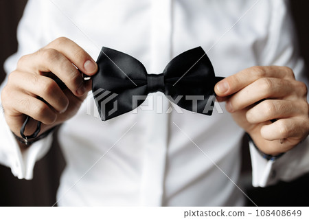 Close up view of man holding black bow tie in hands. Soft focus 108408649