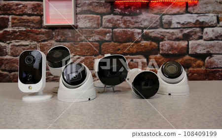 Security cameras of different types are laid out in a row on a demonstration table Security cameras of different types are laid out in a row on a demonstration table 108409199