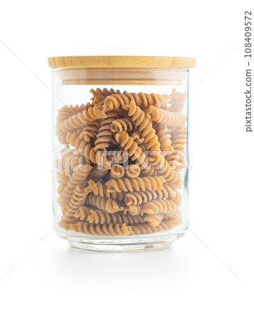 Raw whole grain fusilli pasta. Uncooked pasta in jar isolated on white background. 108409572